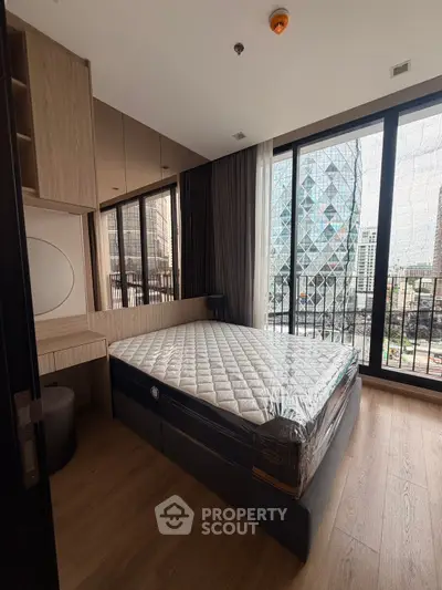 Modern bedroom with floor-to-ceiling windows and city view, featuring a stylish bed and built-in storage.