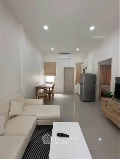 Modern open-plan living room with sleek furniture and kitchen area, perfect for contemporary living.