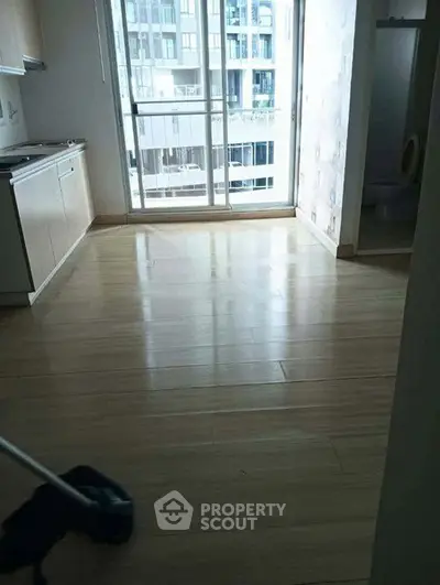 Spacious apartment interior with large windows and modern kitchen area.