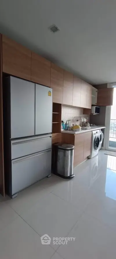 Modern kitchen with sleek cabinets, stainless steel fridge, and washing machine