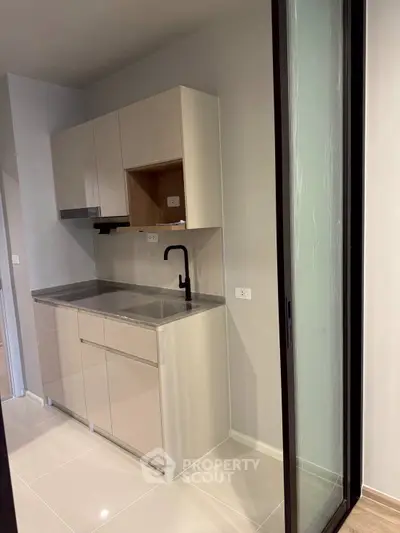 Modern compact kitchen with sleek cabinetry and sliding glass door