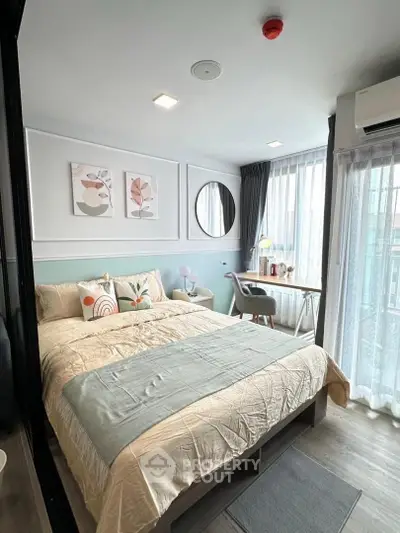 Modern bedroom with stylish decor, large window, and cozy workspace in a bright apartment.