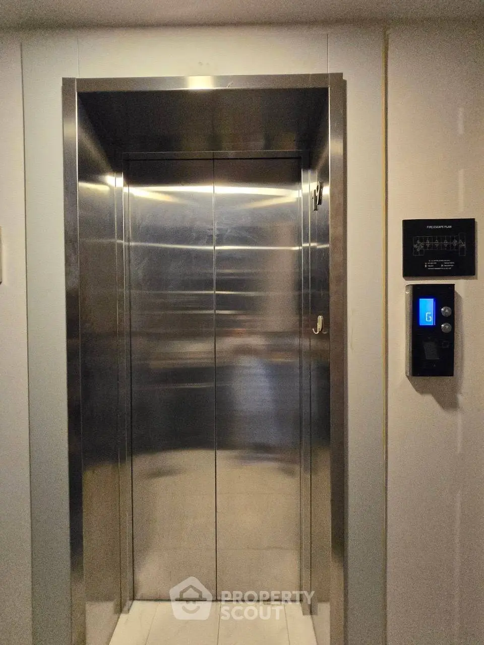 Modern stainless steel elevator in a residential building with digital control panel.