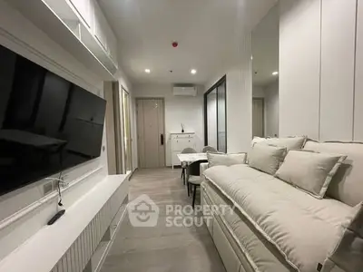Modern living room with sleek design and neutral tones, featuring a large wall-mounted TV and cozy seating area.