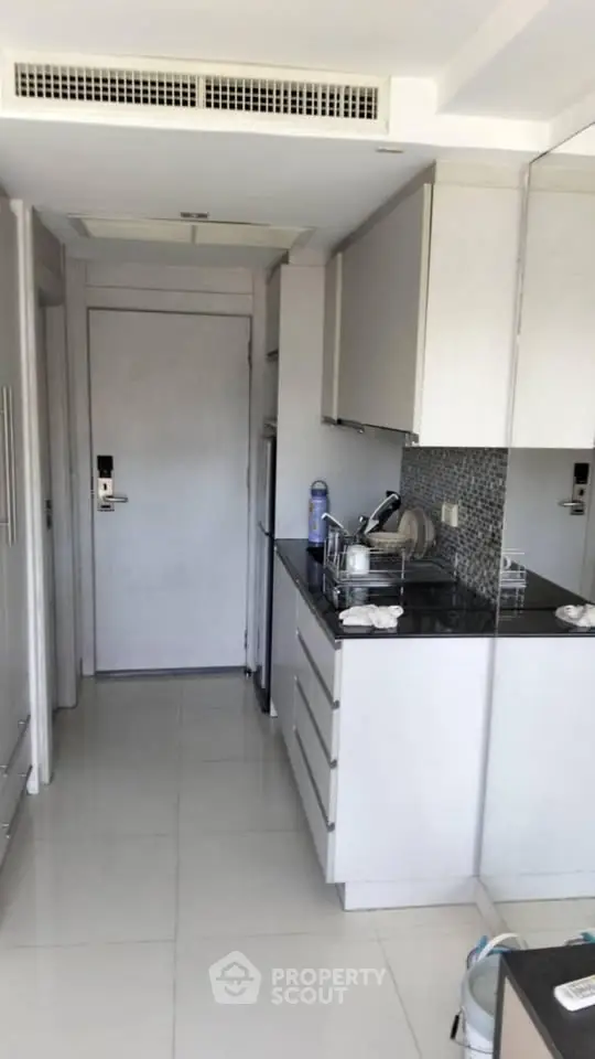 Compact modern kitchen with sleek cabinetry and black countertop in a minimalist apartment.