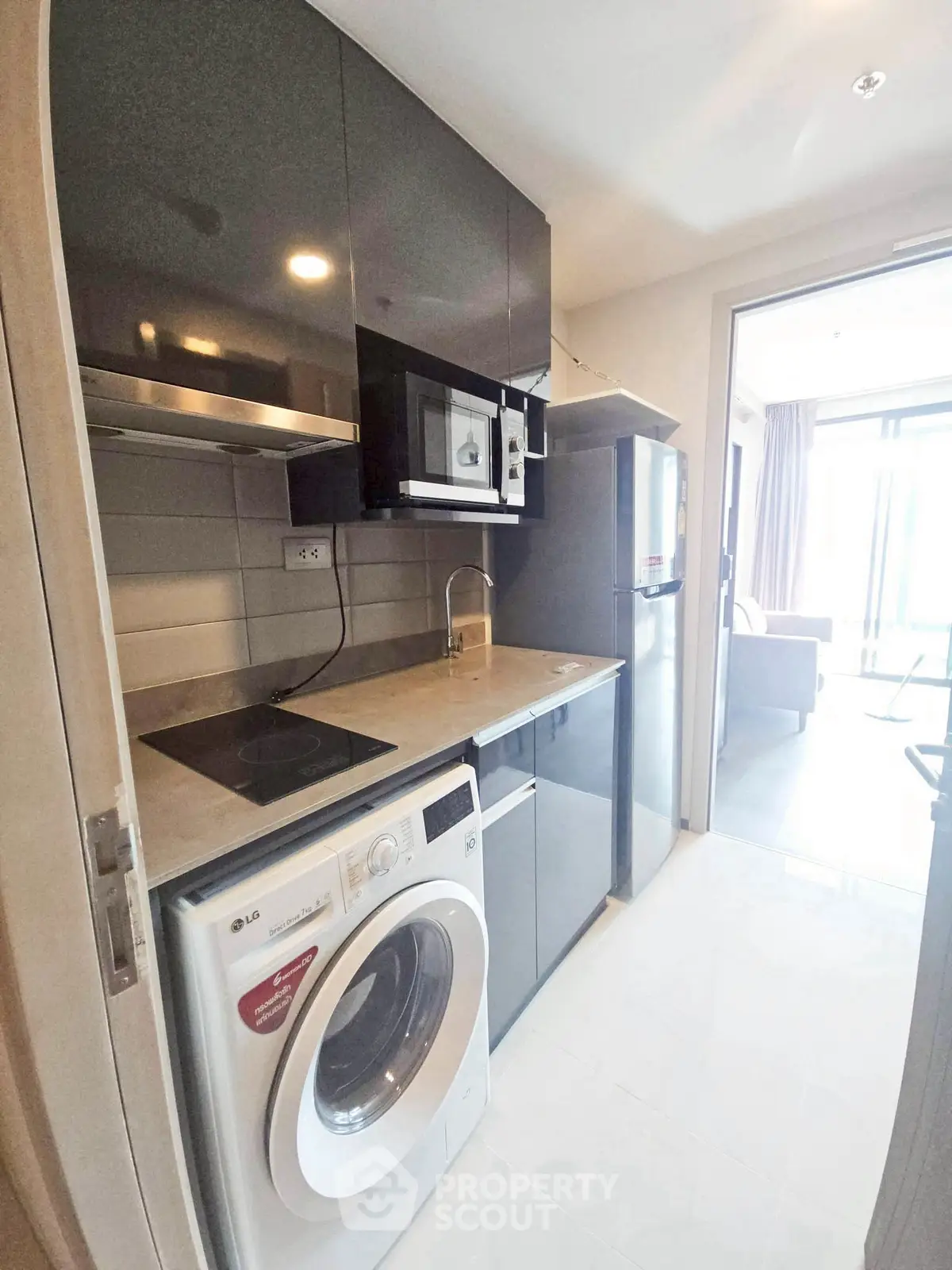 Modern kitchen with sleek appliances and washing machine in compact space