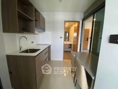 Modern kitchen with sleek cabinetry and dining area in compact apartment