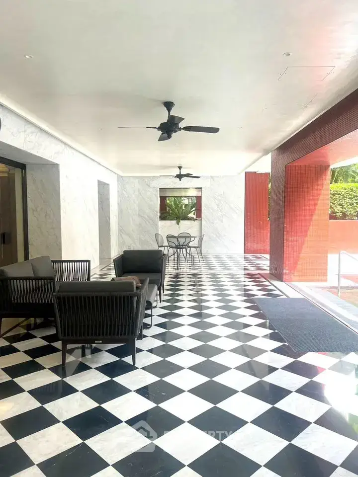 Elegant covered outdoor space with stylish seating and checkered flooring in a modern building.