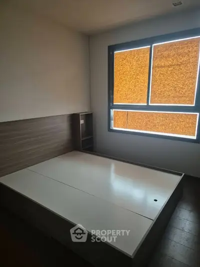 Spacious bedroom with modern bed frame and large window for natural light.