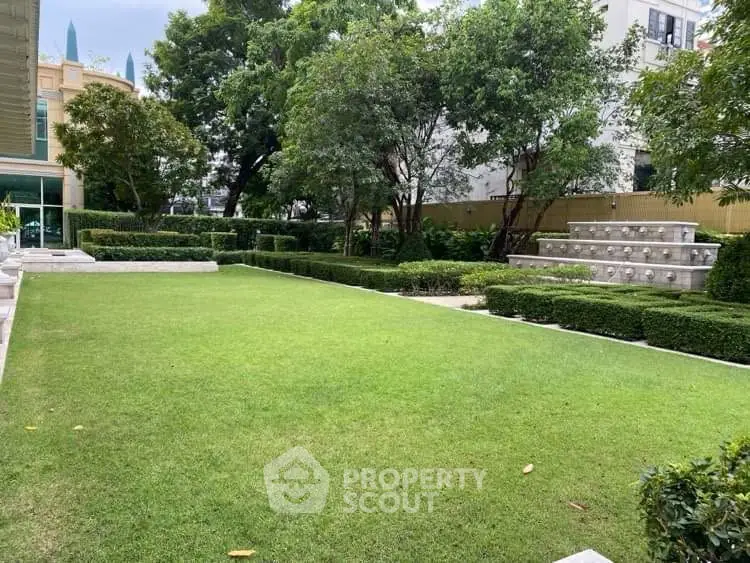 Lush green garden with manicured hedges and trees in a residential complex.