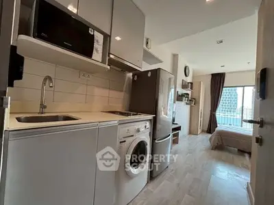 Modern apartment with compact kitchen and cozy bedroom, featuring a washing machine and balcony view.
