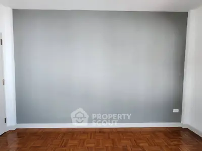 Minimalist empty room with parquet flooring and gray accent wall