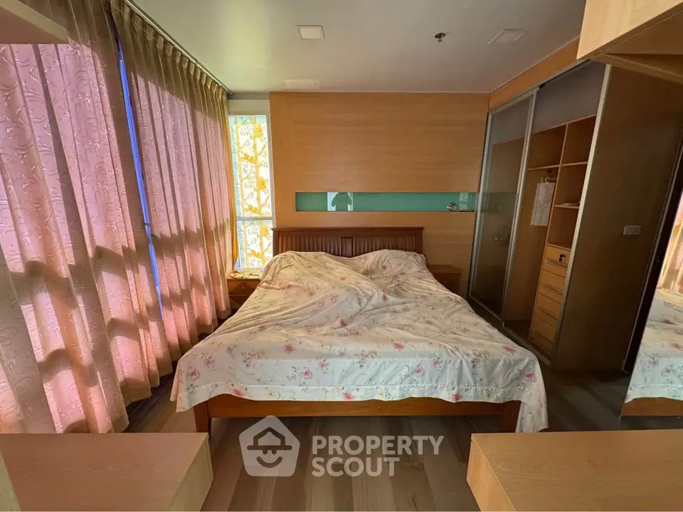 Cozy bedroom with wooden furniture and large windows offering natural light