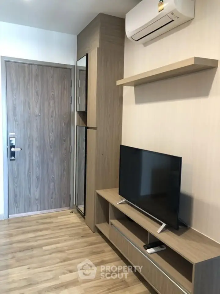 Modern living room with wooden flooring, TV unit, and air conditioning in a stylish apartment.