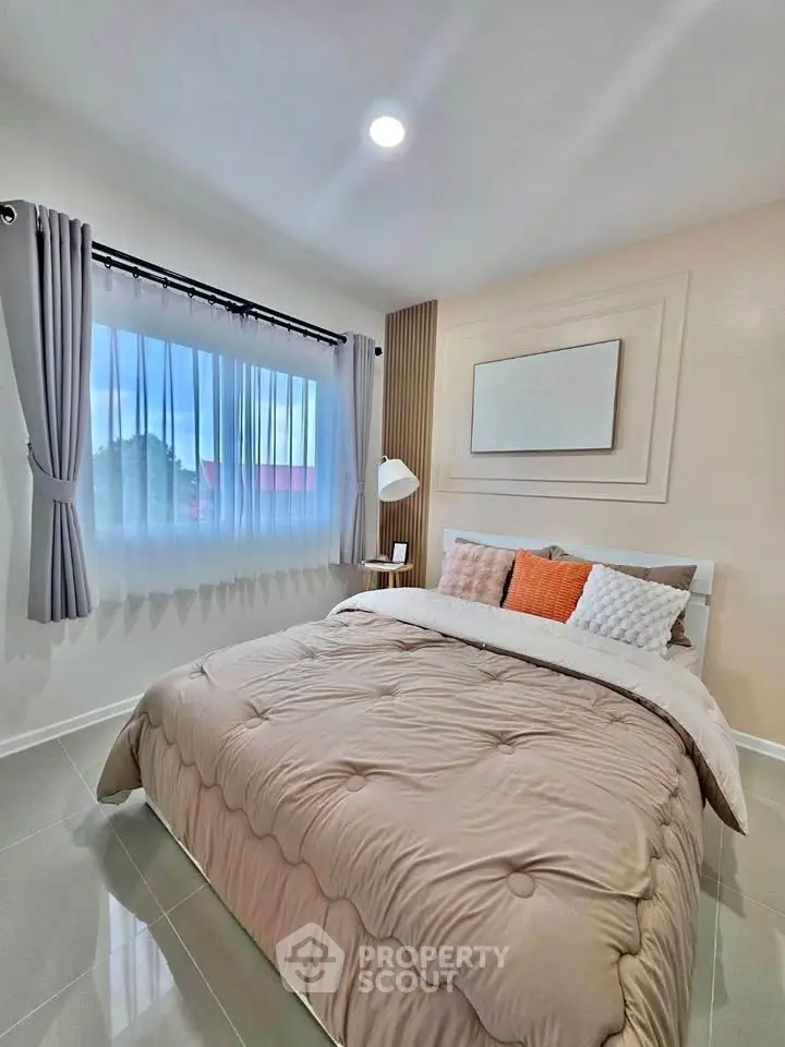 Cozy bedroom with modern decor and large window offering natural light.