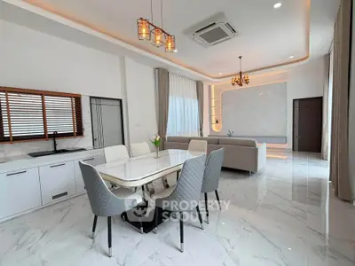 Luxurious open-plan living and dining area with elegant decor and modern lighting.