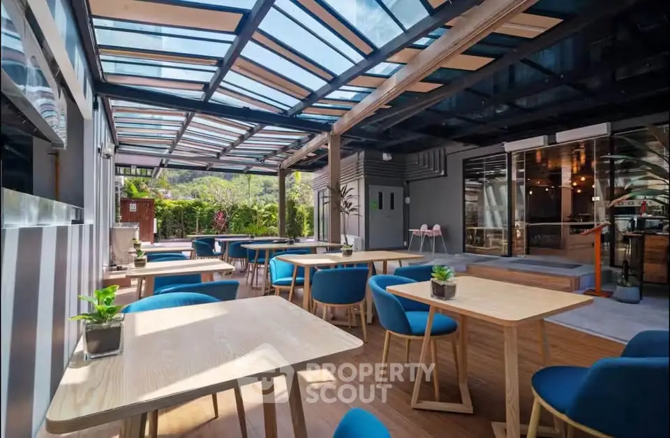 Modern outdoor dining area with glass roof and stylish seating in a vibrant setting.