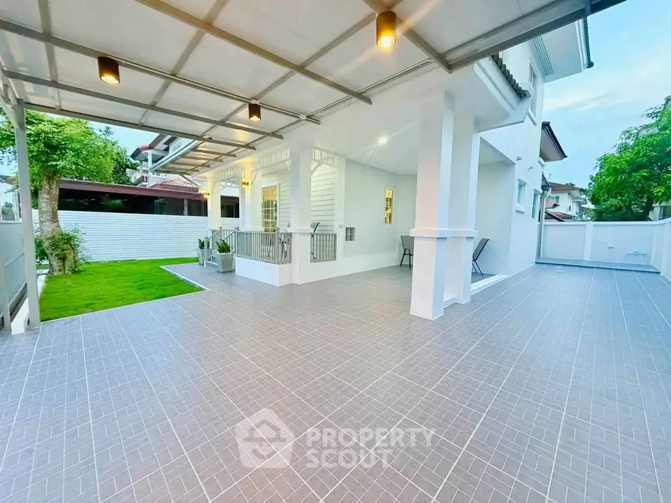 Spacious modern home exterior with covered patio and lush green lawn, perfect for outdoor living.