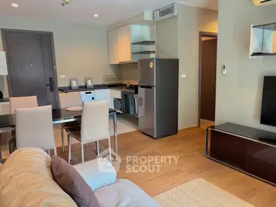 Modern open-plan living room and kitchen with sleek furniture and appliances in a cozy apartment.