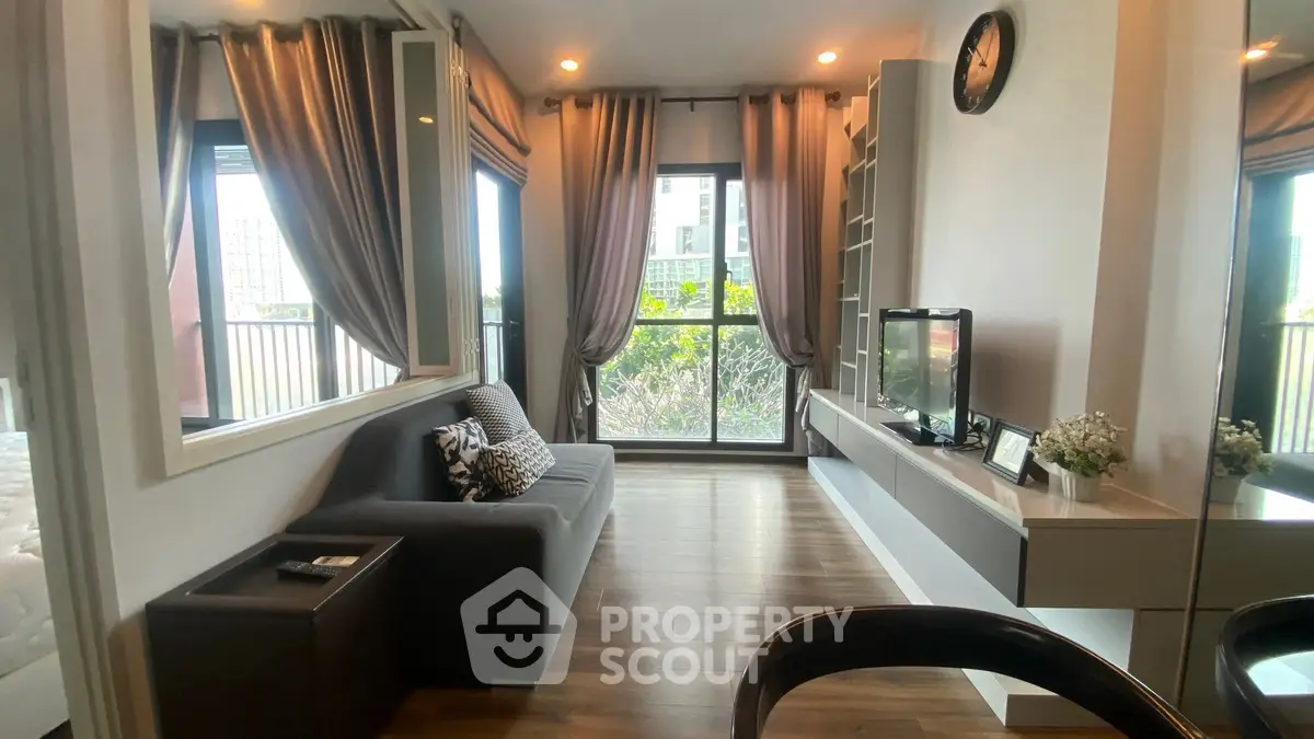 Modern living room with stylish decor and balcony view in urban apartment.