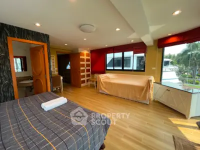 Spacious bedroom with large windows and modern decor, offering a serene view.