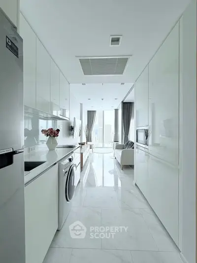 Sleek modern kitchen with white cabinetry and appliances, leading to a bright living area with city views.