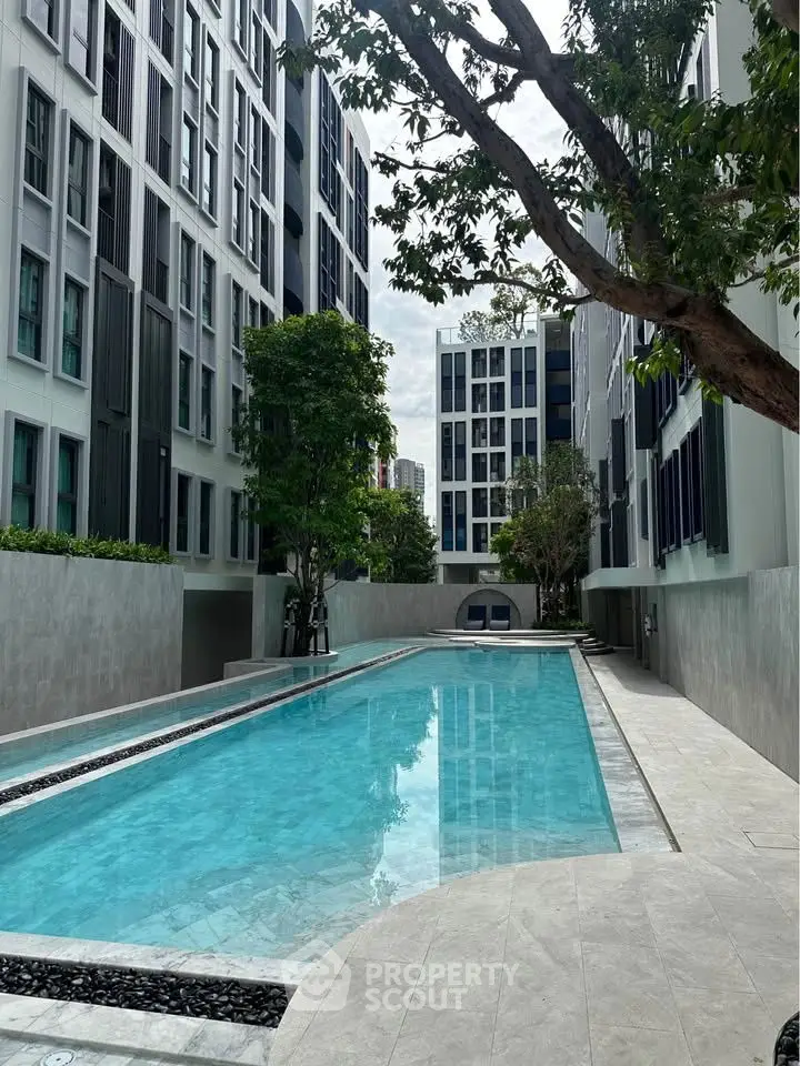Modern apartment complex with a sleek swimming pool and lush greenery.