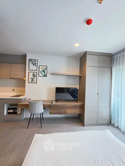 Modern bedroom with stylish desk, TV, and built-in wardrobe in a bright apartment.