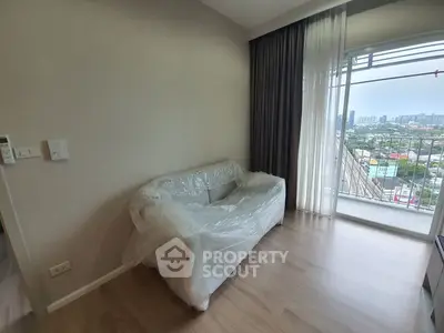 Spacious living room with large windows offering an expansive city view, pristine hardwood floors, and a new sofa still in protective wrapping.