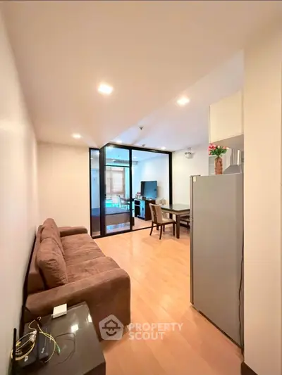 Modern living room with glass partition and sleek furniture in a cozy apartment.
