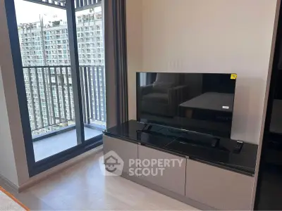 Modern living room with sleek TV stand and balcony view in high-rise apartment.