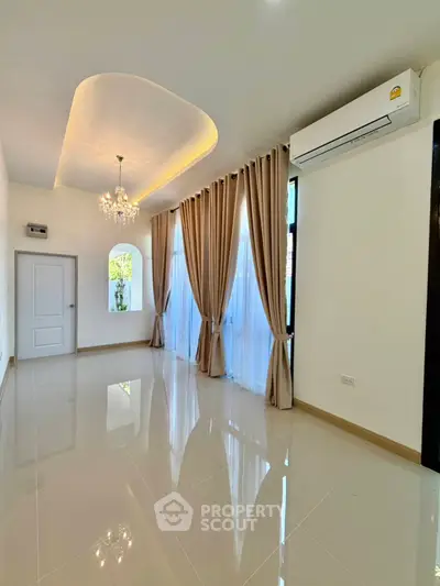 Elegant living room with chandelier and large windows, featuring modern air conditioning.