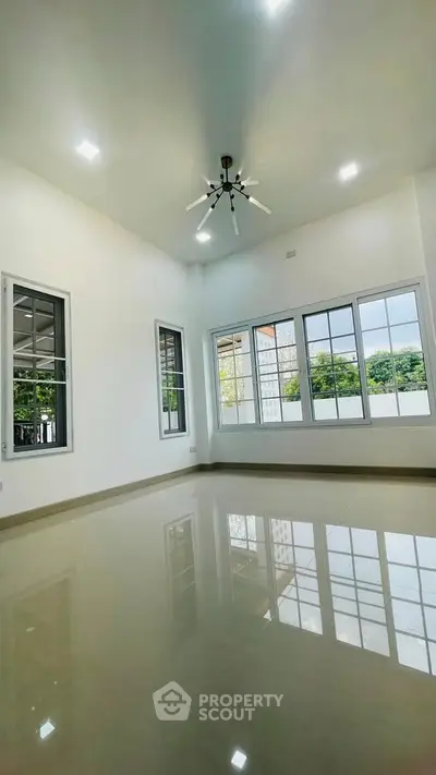 Spacious modern living room with high ceiling and large windows offering natural light and garden view.