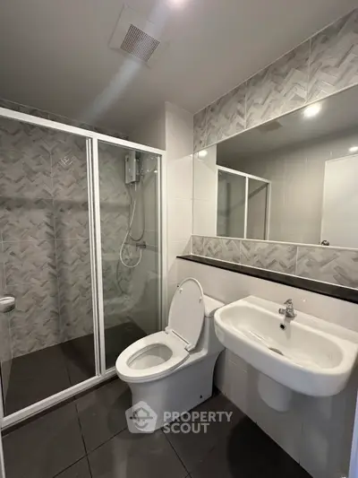 Modern bathroom with glass shower and sleek fixtures in contemporary apartment.