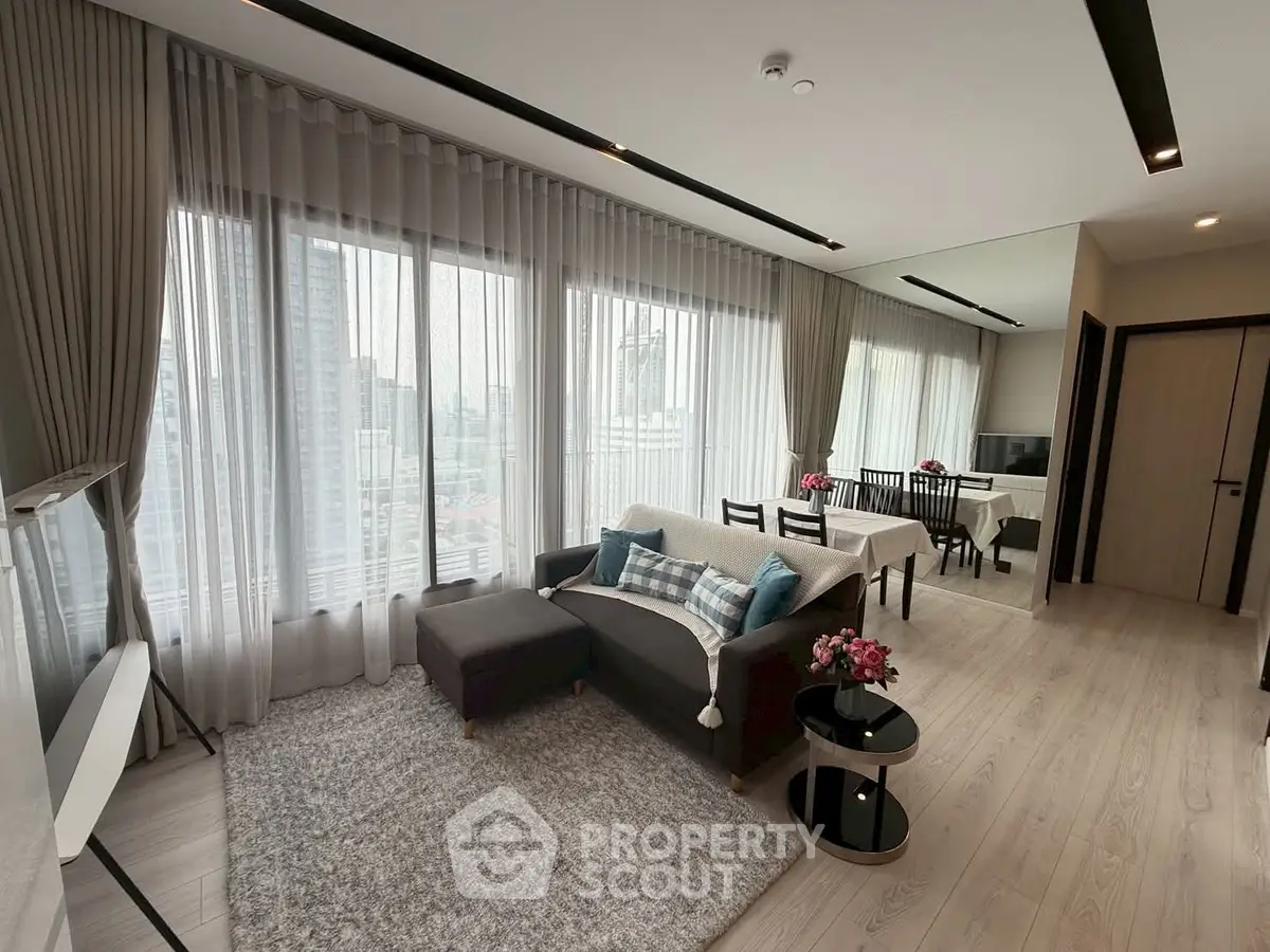 Modern living room with large windows and stylish decor in a high-rise apartment.