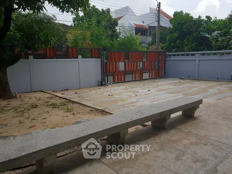 Spacious outdoor area with concrete bench and gated entrance, ideal for relaxation and gatherings.