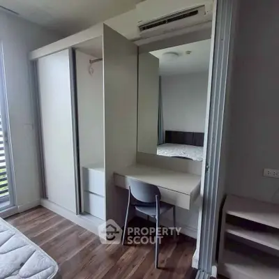 Modern bedroom with sleek wardrobe and study desk, featuring stylish wooden flooring and air conditioning.