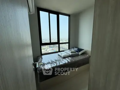 Cozy bedroom with large window offering stunning city views, perfect for urban living.