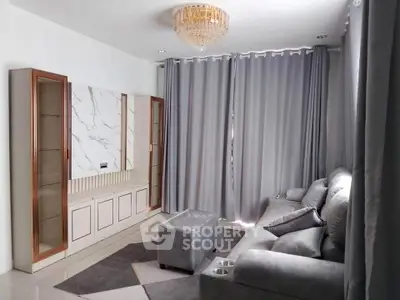 Elegant living room with plush gray sofa, modern decor, and luxurious chandelier.