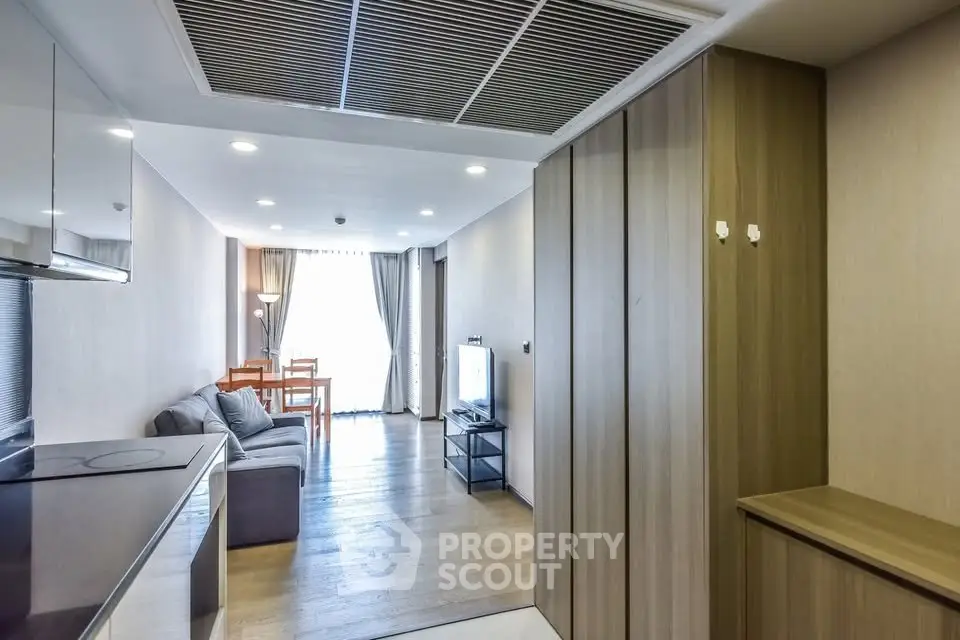 Modern living room with wooden flooring and natural light, featuring a cozy sofa and dining area.
