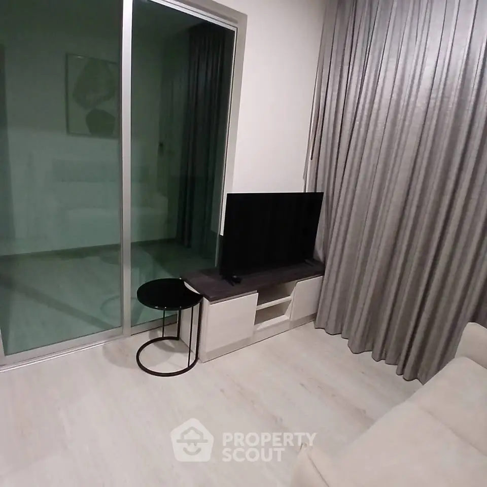 Modern living room with sleek TV stand and glass sliding door leading to balcony.