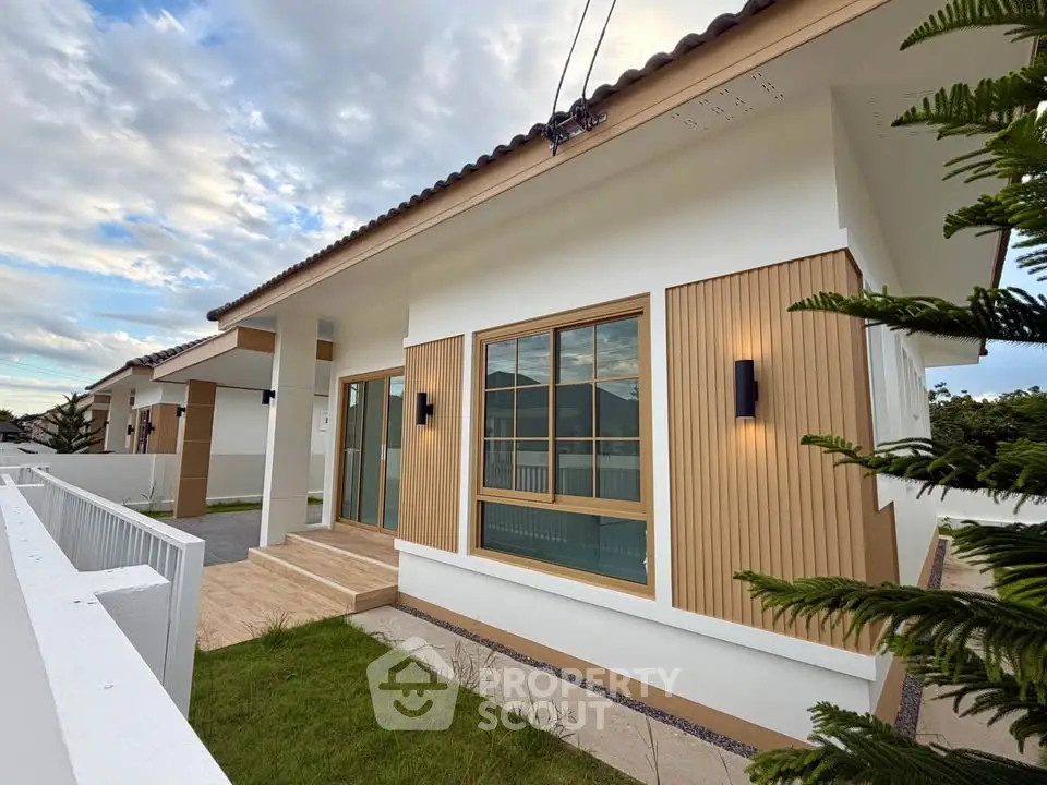 Modern single-story house with stylish exterior and large windows, surrounded by a well-maintained garden.
