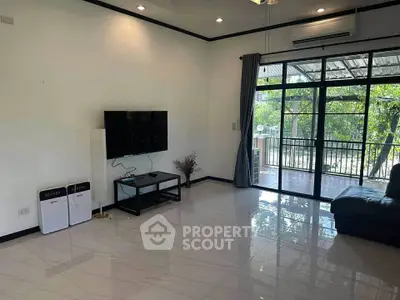Spacious living room with modern decor and large windows overlooking greenery.