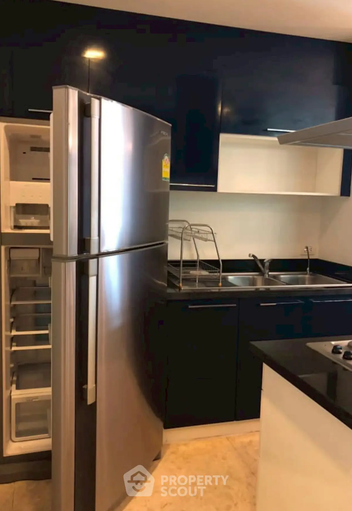 Modern kitchen with sleek black cabinets and stainless steel fridge, perfect for culinary enthusiasts.