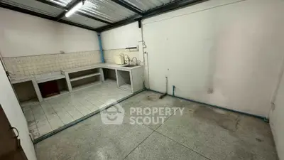 Spacious utility room with tiled countertops and concrete flooring, ideal for laundry or storage use.