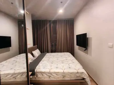 Modern bedroom with cozy bed, mirrored wardrobe, and wall-mounted TV in stylish apartment.