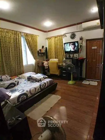 Cozy bedroom with wooden flooring, stylish decor, and ample natural light.