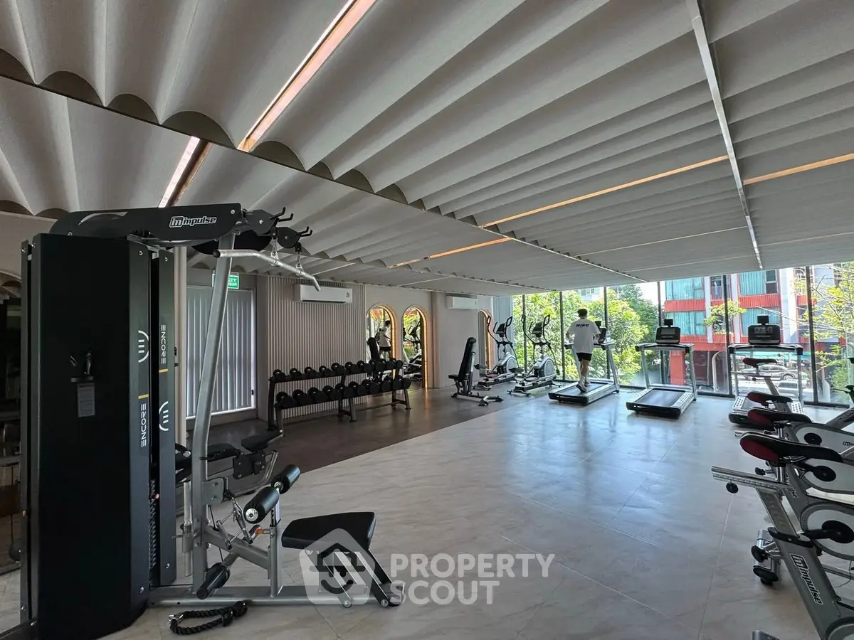 Spacious modern gym with state-of-the-art equipment and large windows offering natural light.