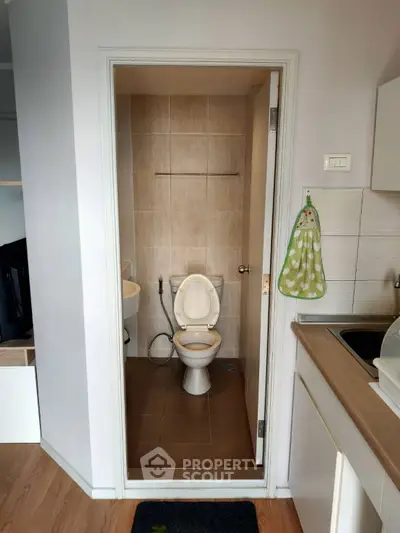 Compact bathroom with modern fixtures and adjacent kitchen area in cozy apartment.