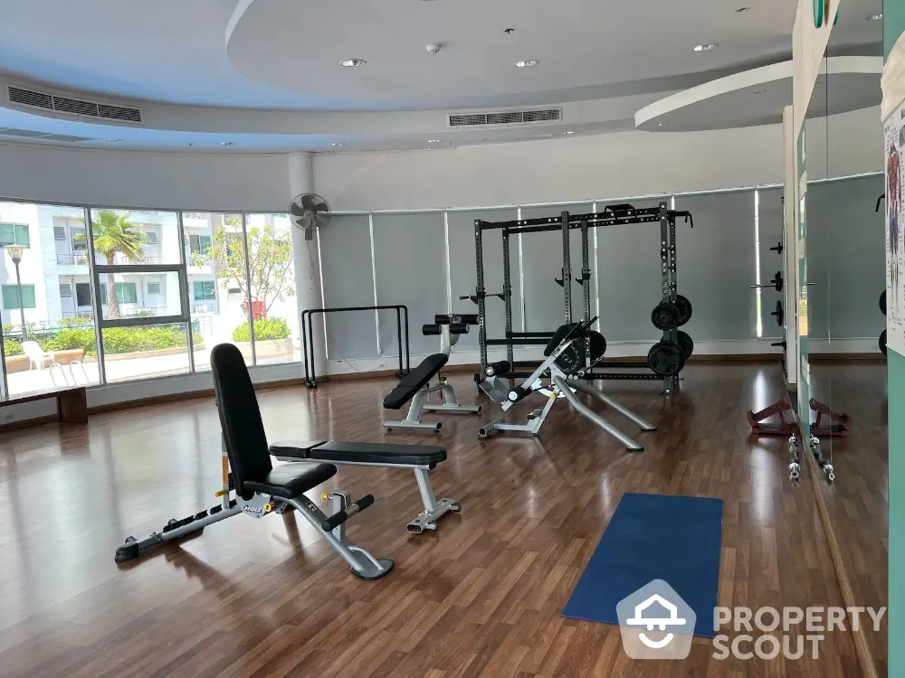 Spacious gym with modern equipment and large windows in luxury apartment complex.